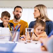 4-köpfige Familie sitzt am Tisch und bespricht